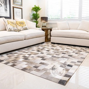 May include: A white sofa with two throw pillows featuring sunflower designs sits in a living room with a white loveseat and a gray and white cowhide rug.