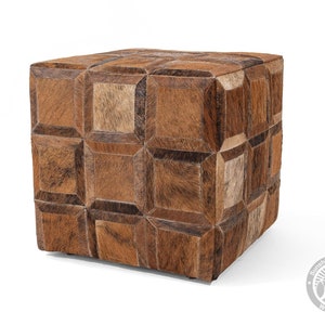 Pu&ograve; includere: Un pouf in pelle marrone con un motivo geometrico. Il pouf &egrave; in pelle di mucca e ha una forma quadrata.
