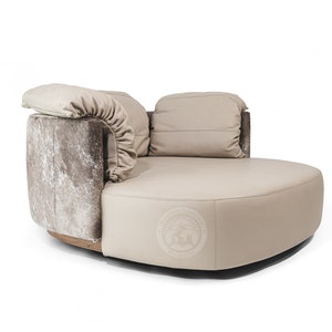 May include: A large, round, off-white leather sofa with two pillows. The sofa has a unique design with a cowhide pattern on the side.