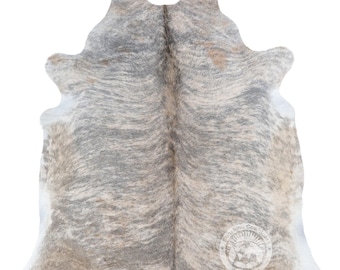 Pode incluir: Um tapete de pele de vaca natural com um padrão manchado em tons de cinzento, branco e castanho claro. A pele tem uma forma orgânica irregular com uma linha central e um logótipo circular no canto inferior direito com a inscrição Sunshine Cowhides.