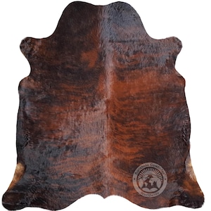May include: Brown and black cowhide rug with a natural, distressed look. The rug has a unique pattern and is made from real cowhide.