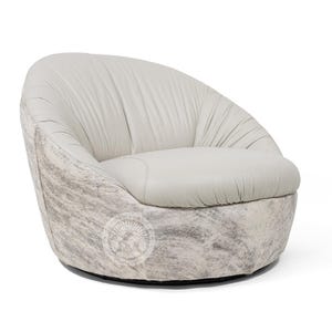 May include: A white leather swivel chair with a cowhide pattern on the base. The chair has a rounded back and a deep seat.