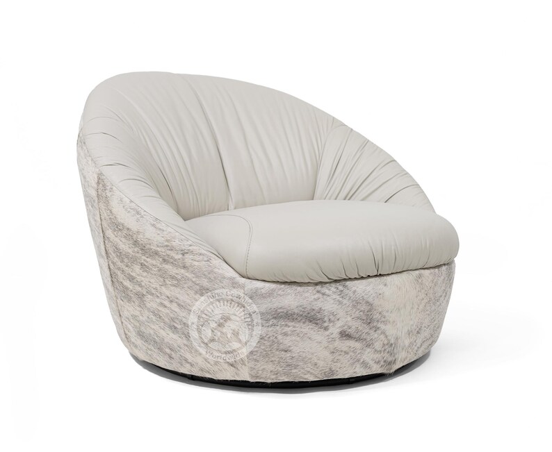 May include: A white leather swivel chair with a cowhide pattern on the base. The chair has a rounded back and a deep seat.