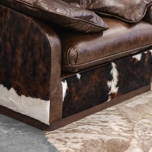 May include: A brown leather armchair with a cowhide pattern on the base and sides. The chair has a tufted back and a thick, padded seat.