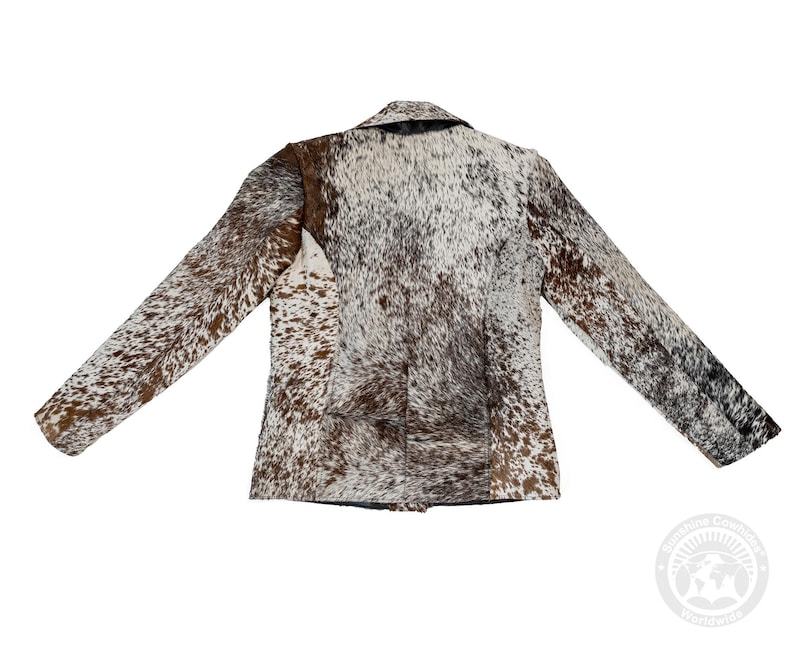 May include: A brown, white, and black cowhide blazer with a notched collar and long sleeves. The jacket has a classic tailored design and a natural, spotted pattern. The back view of the jacket is shown.