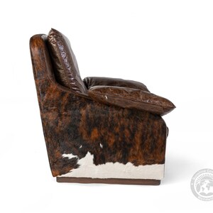 May include: A brown leather armchair with a cowhide pattern. The chair has a high back and a comfortable seat. The chair is upholstered in a soft, durable leather.
