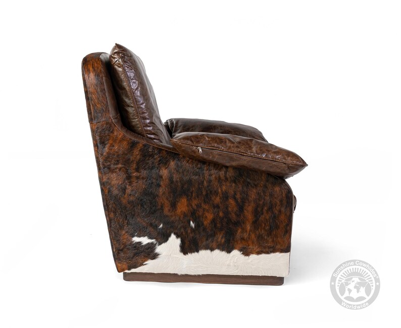 May include: A brown leather armchair with a cowhide pattern. The chair has a high back and a comfortable seat. The chair is upholstered in a soft, durable leather.