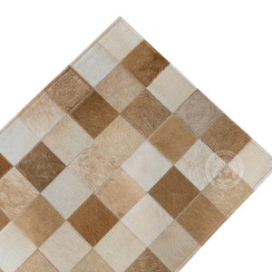 May include: A tan and white cowhide rug with a checkered pattern. The rug is made of individual squares of cowhide sewn together.