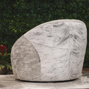 May include: A white and gray cowhide armchair with a tufted back and a rounded shape.