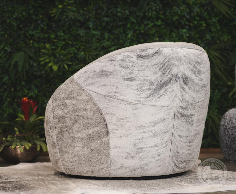 May include: A white and gray cowhide armchair with a tufted back and a rounded shape.