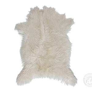 May include: A cream-colored faux fur rug with a long, shaggy pile texture. The rug features an irregular, organic shape with a central seam running vertically down the middle, creating a soft, layered appearance across the entire surface.