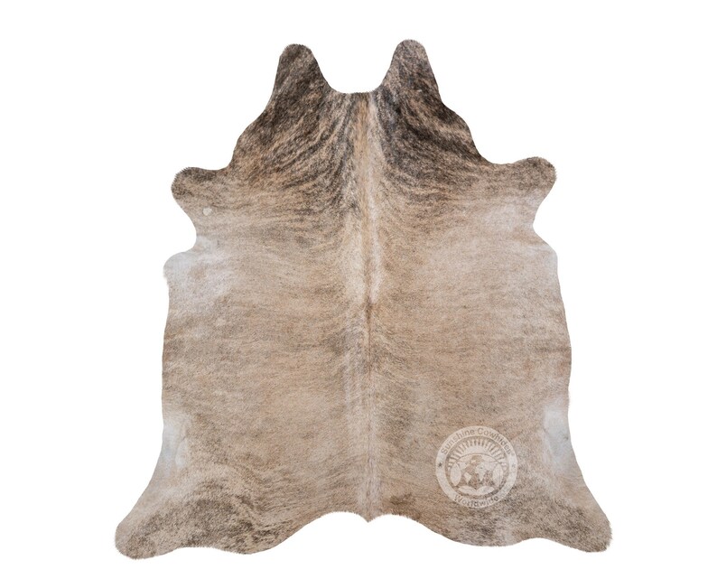 May include: A brown and white cowhide rug with a natural, distressed look. The rug has a unique pattern of dark brown and light brown markings.