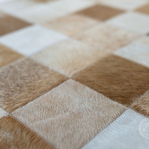 May include: A close-up of a checkered cowhide rug with alternating light and dark brown squares. The rug is made of soft, natural cowhide and has a unique, rustic look.