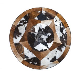 May include: A round cowhide rug with a star design in the center. The rug features a patchwork pattern of brown, black, and white cowhide pieces. The rug has a diameter of approximately 60 inches.