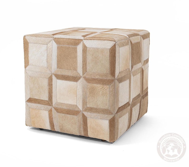 K&ouml;nnte beinhalten: Ein quadratischer Hocker mit einem geometrischen Muster aus beigefarbenem und hellbraunem Rindsleder. Der Hocker besteht aus mehreren zusammengen&auml;hten Lederst&uuml;cken.