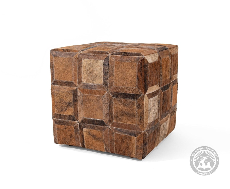 Pu&ograve; includere: Un pouf in pelle marrone con un motivo geometrico. Il pouf &egrave; in pelle di mucca e ha una forma quadrata.
