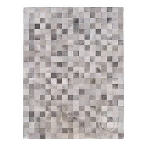 May include: A gray and white patchwork rug made of cowhide. The rug is made up of small squares of leather, each with a different pattern and shade of gray.