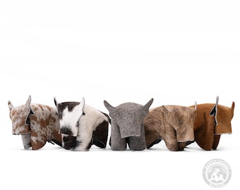 May include: Five small, plush cowhide sculptures in different colours and patterns. The sculptures are arranged in a row, facing the viewer. The sculptures are made of soft, fuzzy material and have a realistic appearance.