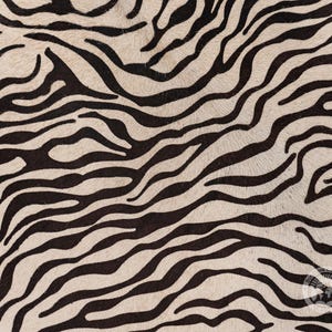 May include: Black and white zebra print fabric with a soft, fuzzy texture.