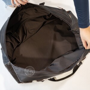May include: A large dark brown leather travel bag with a spacious interior lined in dark brown fabric. The exterior features patches of white and brown cowhide fur. A circular logo with the text Sunshine Cowhides Worldwide is visible.