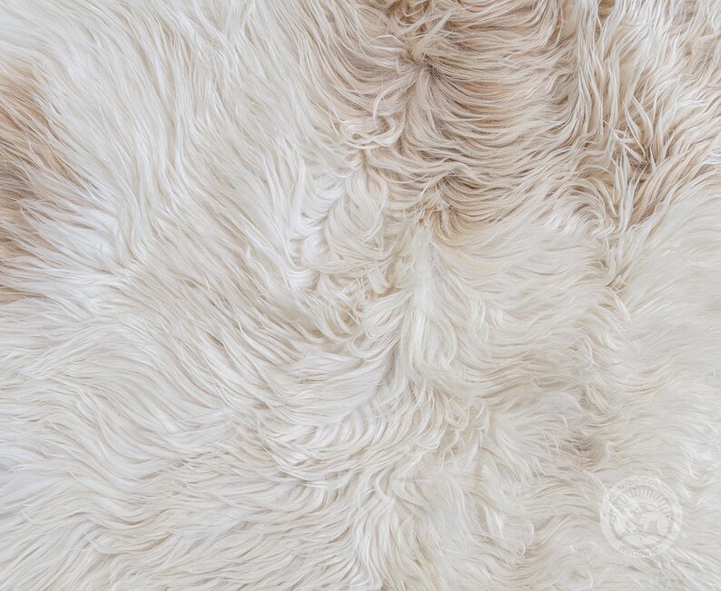 May include: A long-pile faux fur rug featuring a blend of cream, off-white, and light beige tones. The texture consists of dense, wavy synthetic fibers that create a soft, layered appearance across the entire surface of the textile material.