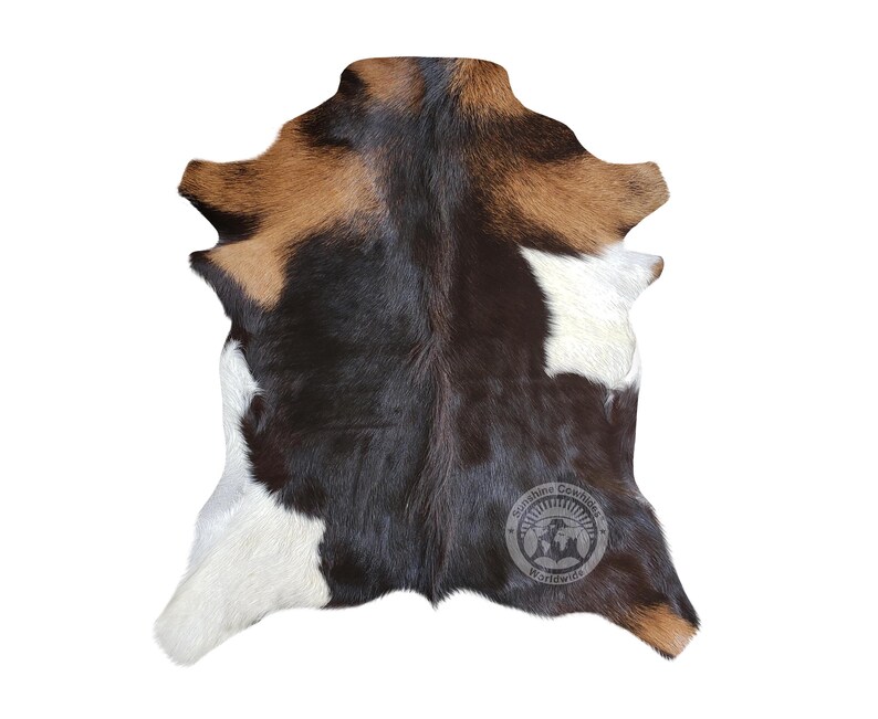 Puede incluir: Una alfombra de piel de vaca con parches negros, blancos y marrones. La alfombra mide aproximadamente 90 cm por 120 cm.