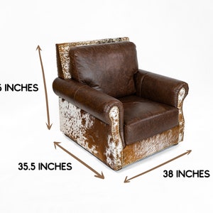 May include: Brown leather armchair with a cowhide pattern on the bottom and sides. The chair is 36 inches tall, 35.5 inches wide, and 38 inches deep.