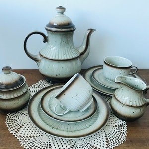 Puede incluir: Un juego de té vintage de cerámica marrón y blanca moteada con una tetera, un azucarero, una jarra de crema y dos tazas y platillos.