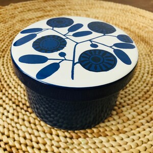 K&ouml;nnte beinhalten: Ein blauer und wei&szlig;er Keramikbeh&auml;lter mit einem Blumendesign. Der Deckel hat einen wei&szlig;en Hintergrund mit blauen Blumen und Bl&auml;ttern. Der Beh&auml;lter ist blau.