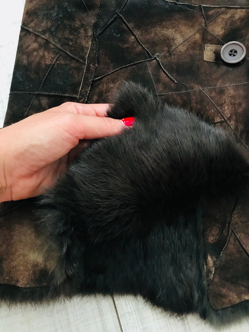 May include: A brown leather jacket with a black fur collar. The jacket is made of patchwork leather and has a button closure.