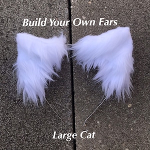 May include: Two white faux fur cat ears with wire frames. The text "Build Your Own Ears" and "Large Cat" are visible below the ears.