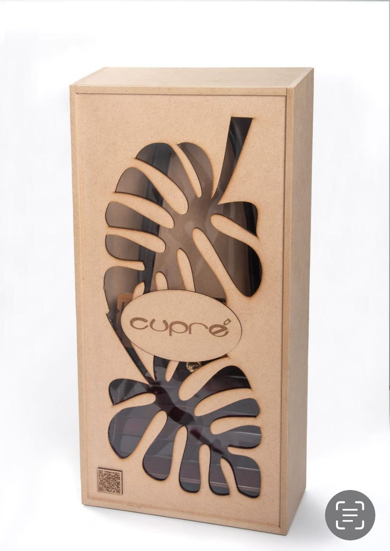May include: A rectangular wooden box with a cut-out leaf design. The box has a clear window revealing the contents. The word "cupre" is displayed on an oval-shaped wooden label. The box is a natural wood colour.
