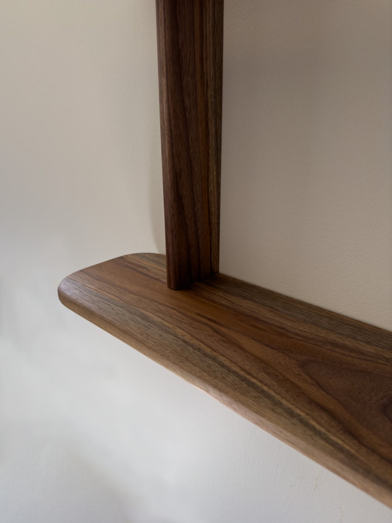 K&ouml;nnte beinhalten: Nahaufnahme einer Holzregal mit abgerundeter Kante, aus dunkelbraunem Holz mit nat&uuml;rlicher Maserung.