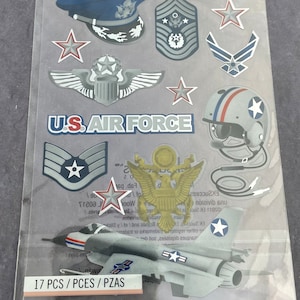 May include: A sheet of U.S. Air Force themed stickers. The stickers include images of aircraft, stars, a pilot's helmet, military insignia, and the words "U.S. AIR FORCE". The sheet contains 17 pieces.