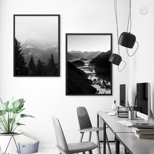 May include: Two black and white framed photographs of mountain landscapes. The top photo shows a mountain range with trees in the foreground. The bottom photo shows a valley with a river winding through it.