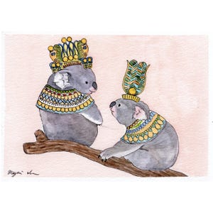 May include: A watercolour illustration featuring two koalas adorned with Egyptian-style headdresses and collars, sitting on a brown branch against a pale pink backdrop. The koalas are grey with colourful, detailed decorations.