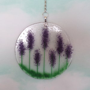May include: A round glass suncatcher with a silver chain, featuring a design of purple lavender flowers with green stems on a white background.
