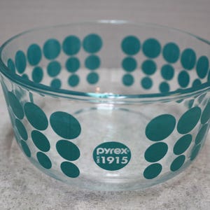 May include: A clear glass mixing bowl with a teal polka dot pattern. The bowl has the Pyrex logo and the text "Since 1915" printed on the bottom.