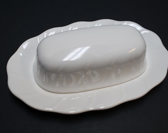 May include: White ceramic butter dish with a lid. The lid has a decorative design of Hebrew letters.