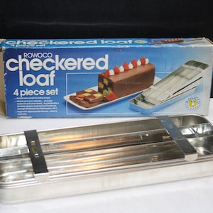May include: A Rowoco checkered loaf baking pan set, a 4 piece set, in a blue and white box with a picture of a loaf of cake. The pan is made of silver metal and has a rectangular shape.