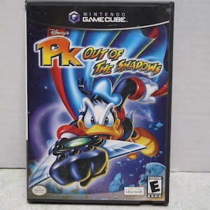 May include: A Nintendo GameCube video game case for Disney's PK Out of the Shadows. The cover features a graphic illustration of Donald Duck in a superhero costume with a cape and a metallic glove, set against a dark blue space background.