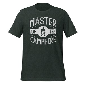 May include: A dark charcoal heather gray short-sleeve t-shirt featuring a white distressed graphic print on the chest. The design includes the text MASTER OF THE CAMPFIRE surrounding a central circular icon of a burning campfire with logs.