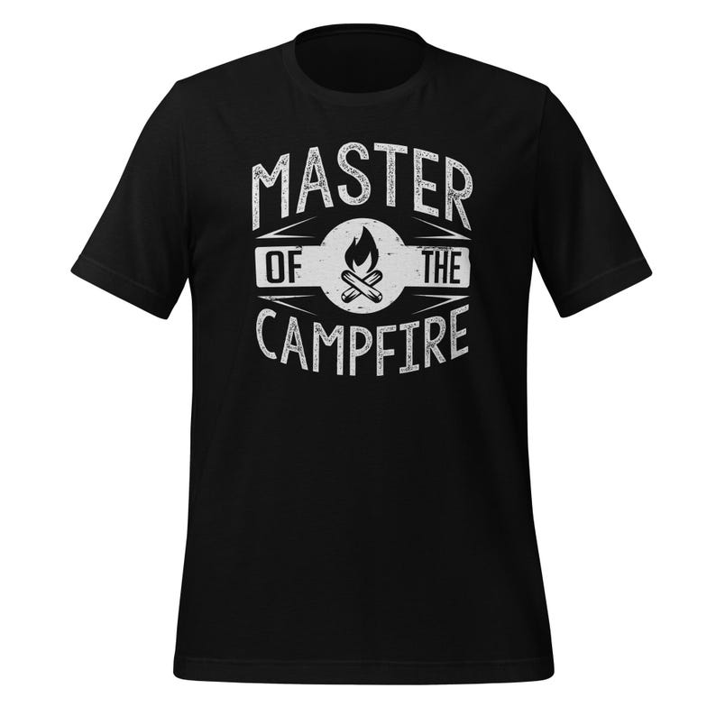 May include: A black short-sleeved t-shirt featuring a white distressed graphic on the chest. The design includes the text "MASTER OF THE CAMPFIRE" surrounding a central circular emblem that depicts a stylized campfire with flames and logs.