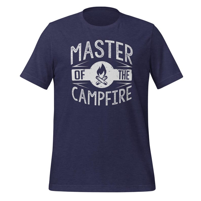 May include: A navy blue short-sleeve t-shirt featuring a white distressed graphic on the chest. The design includes a central campfire icon inside a circle, surrounded by the text "MASTER OF THE CAMPFIRE" in a bold, capitalized, sans-serif font.