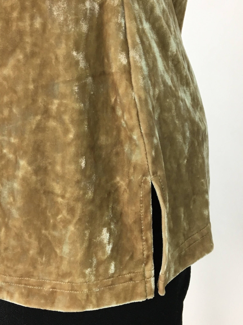 May include: A gold velvet top with a side slit. The fabric has a subtle shimmer.