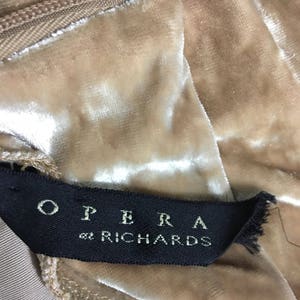 May include: A close-up of a beige velvet fabric with a black label that reads "OPERA by RICHARDS".