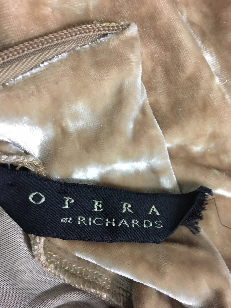 May include: A close-up of a beige velvet fabric with a black label that reads "OPERA by RICHARDS".