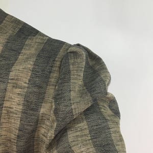 Puede incluir: Primer plano de una tela de rayas marrones y negras con un tejido texturizado. La tela tiene una textura ligeramente hinchada, lo que sugiere que podr&iacute;a ser una prenda de vestir.