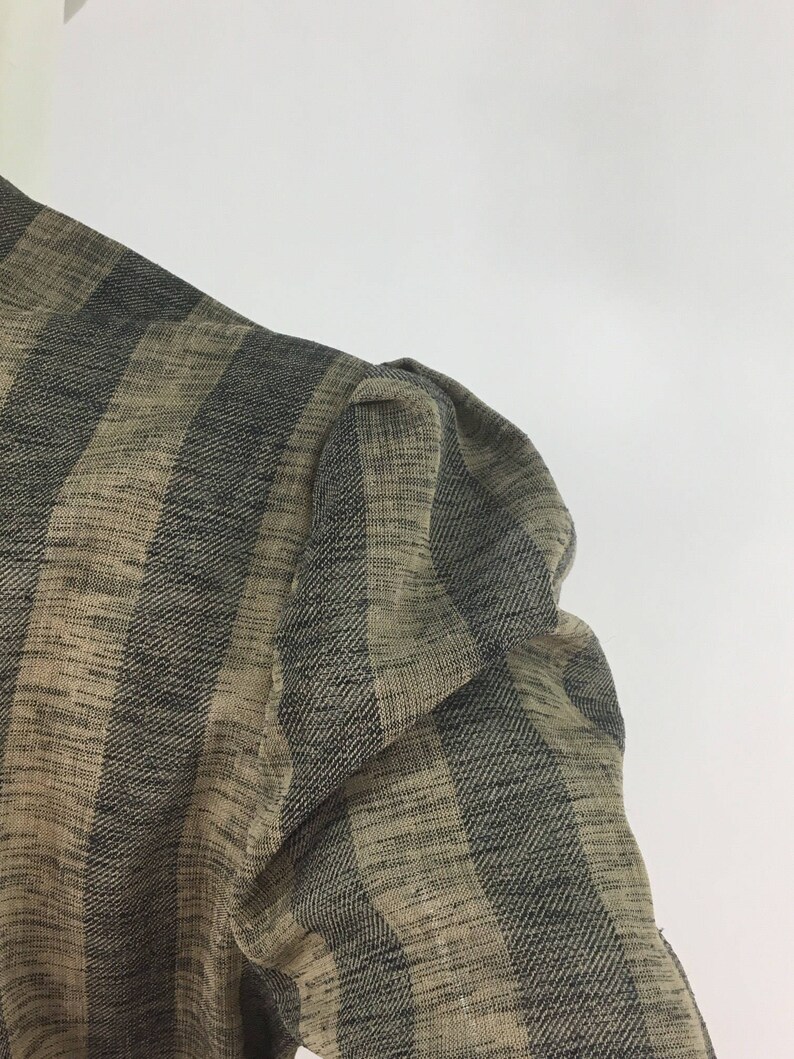 Puede incluir: Primer plano de una tela de rayas marrones y negras con un tejido texturizado. La tela tiene una textura ligeramente hinchada, lo que sugiere que podr&iacute;a ser una prenda de vestir.