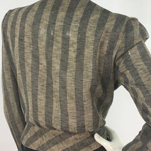 Puede incluir: Una camisa de manga larga a rayas marrones y negras con cuello en V. La camisa tiene un corte holgado y est&aacute; hecha de una tela ligera.